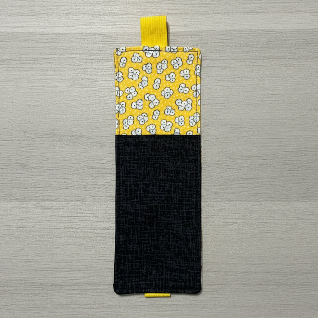Rectangular pouch with yellow floral top half and black bottom half on a light gray background
